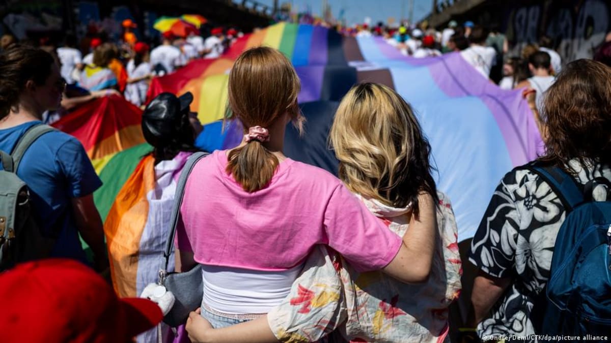 Large crowd of people marching with rainbow flags during Prague Pride parade celebration
