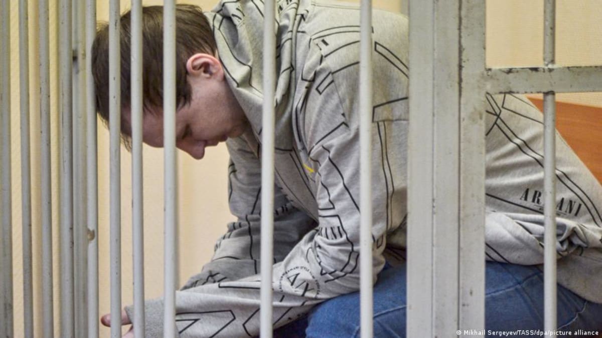Robert Gilman holding American flag on plane with mother after release from Russian prison