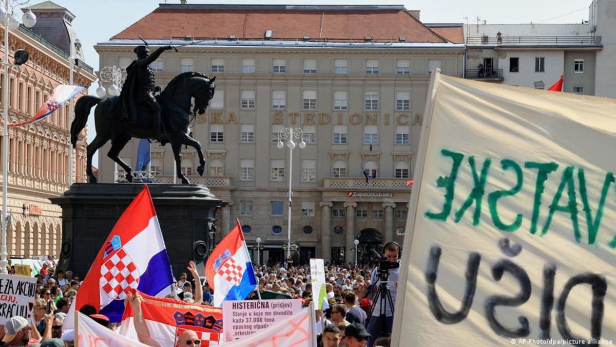 Large crowd of protesters waving Croatian flags in Zagreb streets demanding toxic waste cleanup