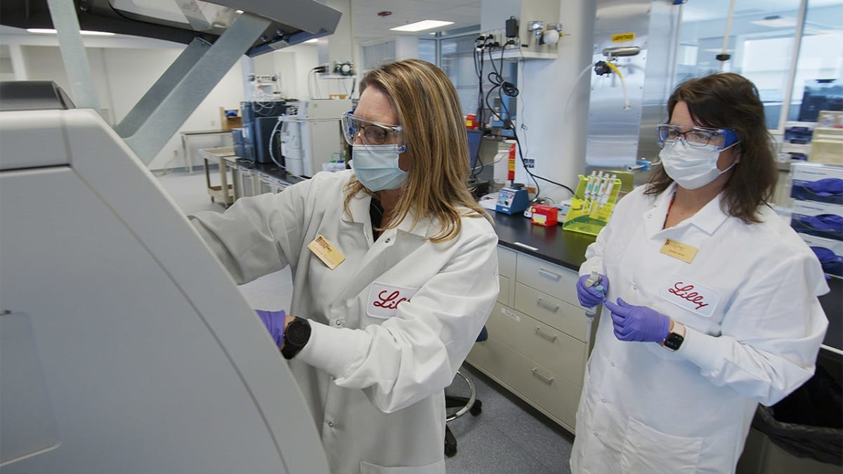 Modern pharmaceutical manufacturing facility with scientists working in clean room laboratory environment