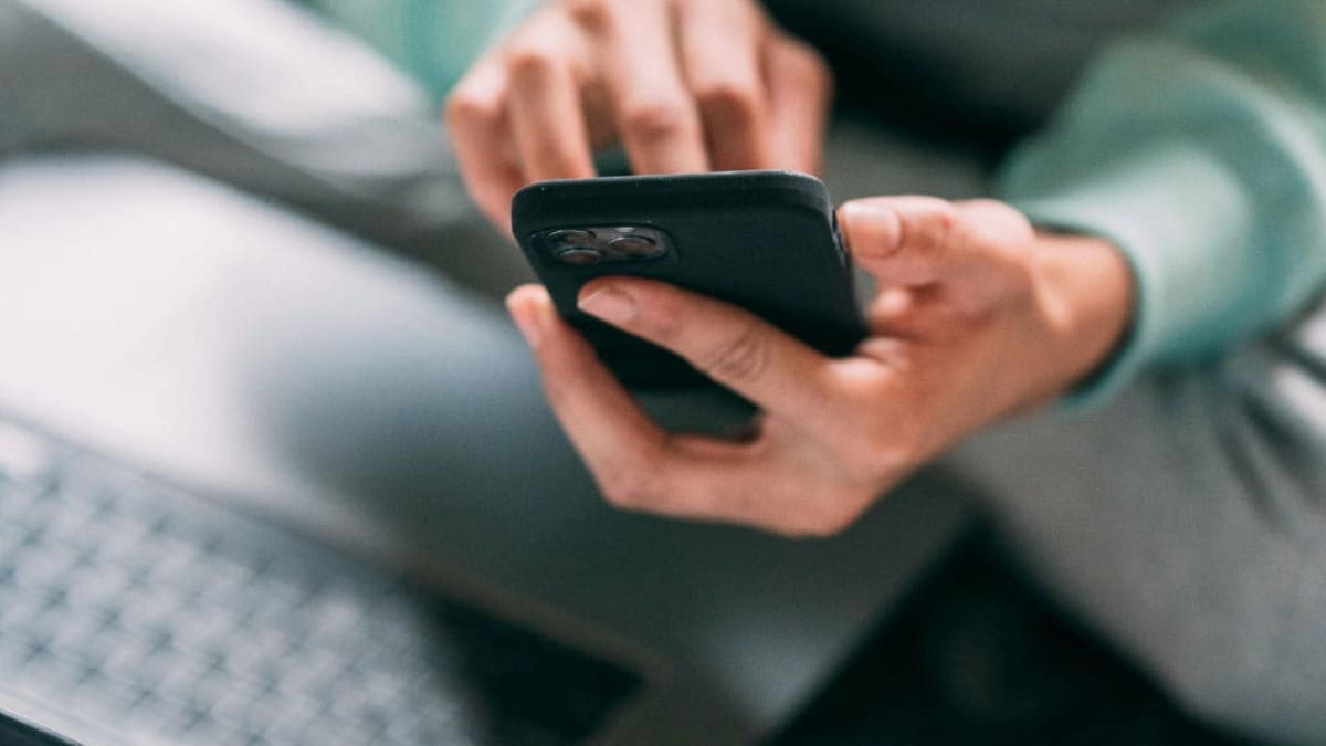 Person looking relieved while checking smartphone with fewer spam call notifications on screen
