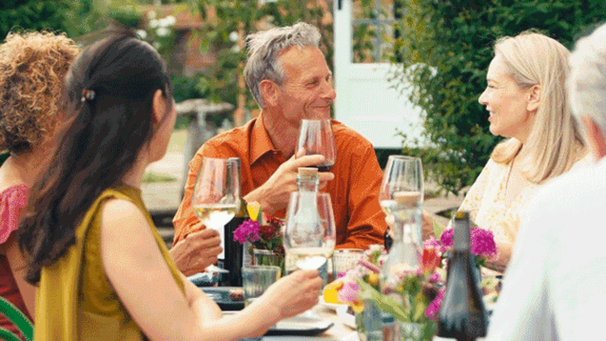 Glass of red wine being poured at dinner table with healthy food