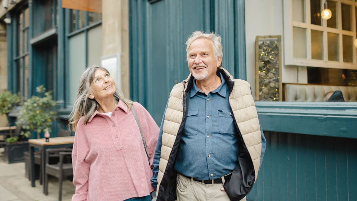 Elderly residents walking together on tree-lined street in dementia-friendly community village