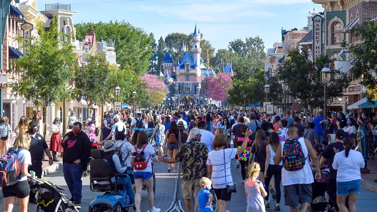 Visitors walking through Disneyland Park entrance with castle visible in background
