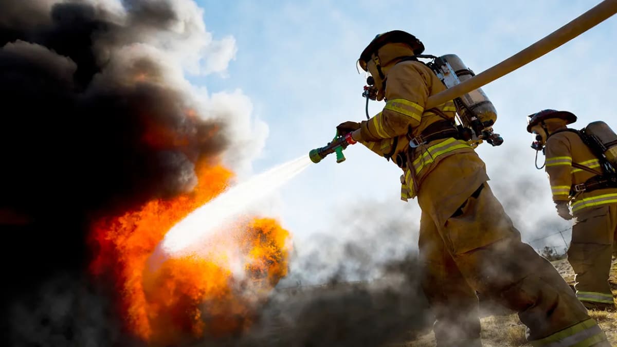 CAL FIRE firefighter Mike Morlan in uniform standing beside fire truck equipment