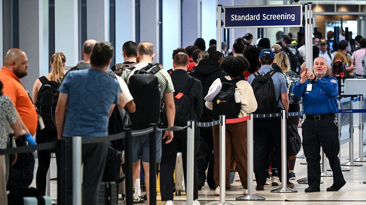 Crowded airport terminal with long TSA security line extending beyond doors