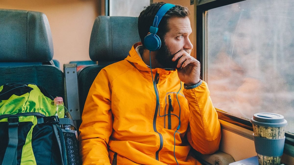 Person wearing headphones while commuting, enjoying an audiobook on their smartphone