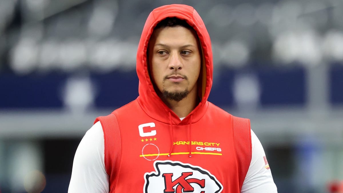 Patrick Mahomes throwing football in practice wearing black compression sleeve on injured knee