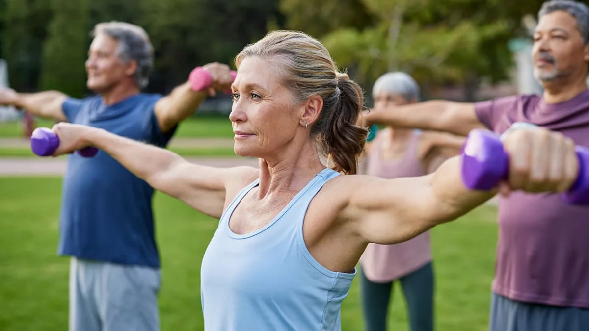 Smiling older woman performing strength training exercise with resistance band at home