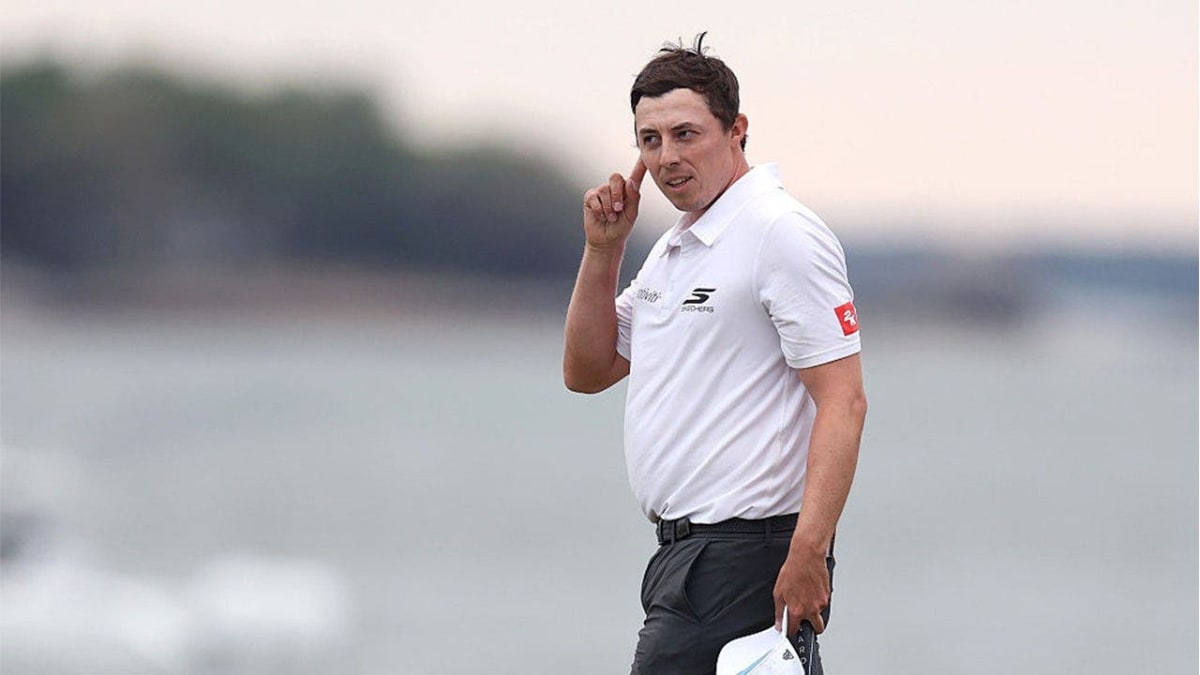 Matt Fitzpatrick putting finger to ear celebrating after playoff victory at golf tournament