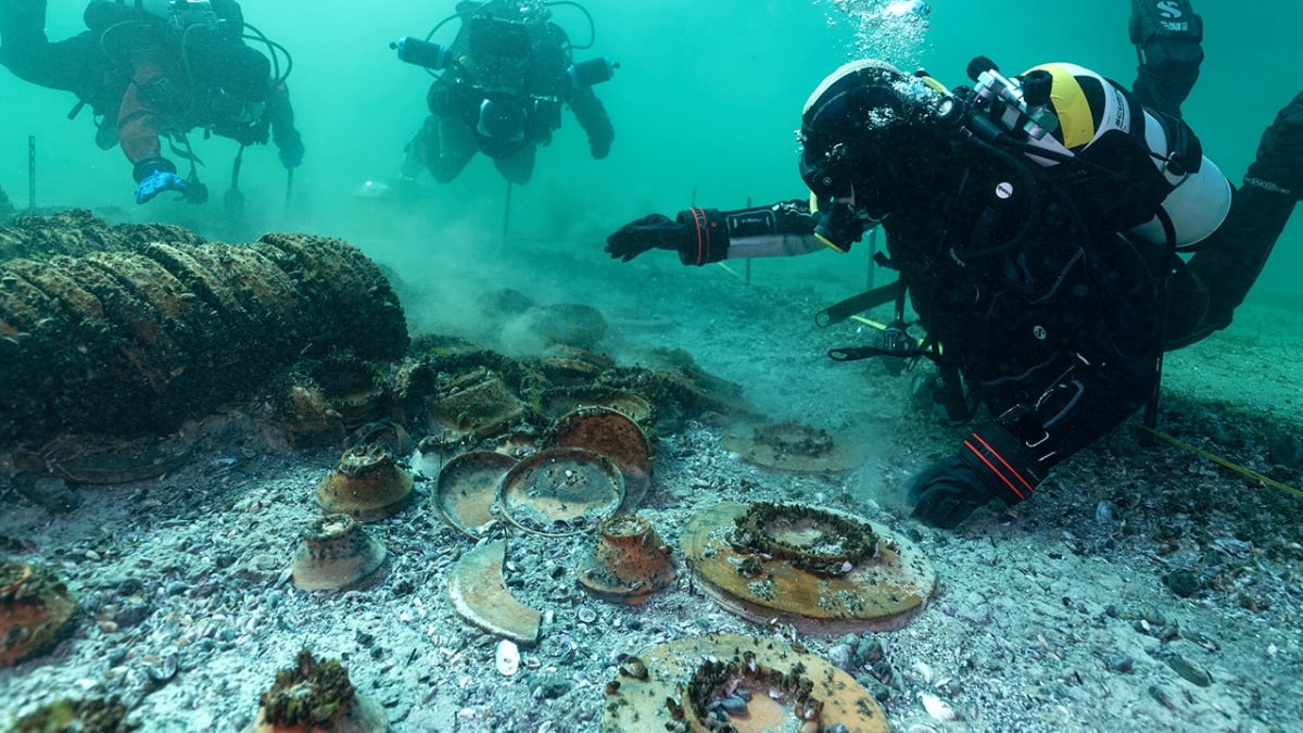 Underwater archaeologists examining ancient Roman ceramic dishes and artifacts on Swiss lakebed