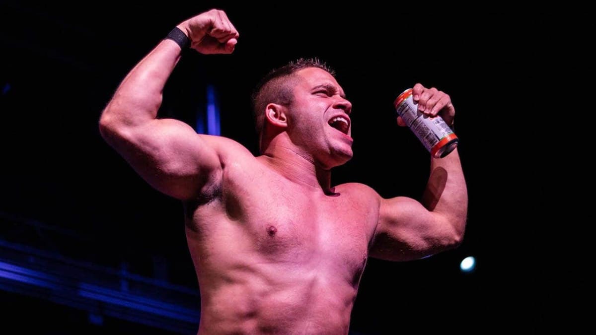 Professional wrestler Vinny Pacifico flexing in the ring for an enthusiastic crowd
