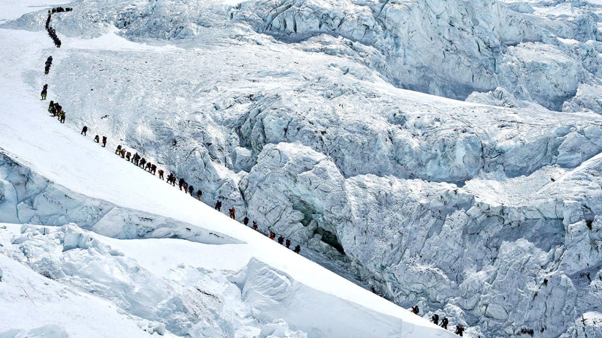Long line of mountaineers ascending snowy slopes toward Mount Everest summit in Nepal