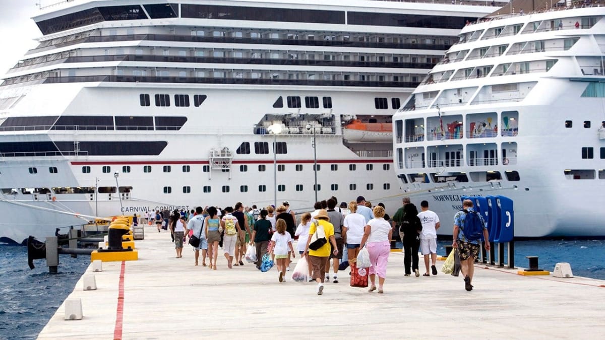 Large cruise ship sailing on blue ocean water under sunny skies with passengers aboard