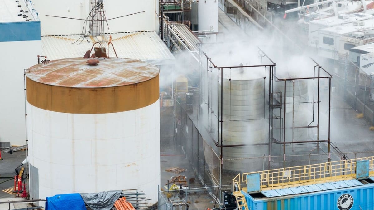 Firefighters spray water on large industrial chemical tank at aerospace facility in Garden Grove