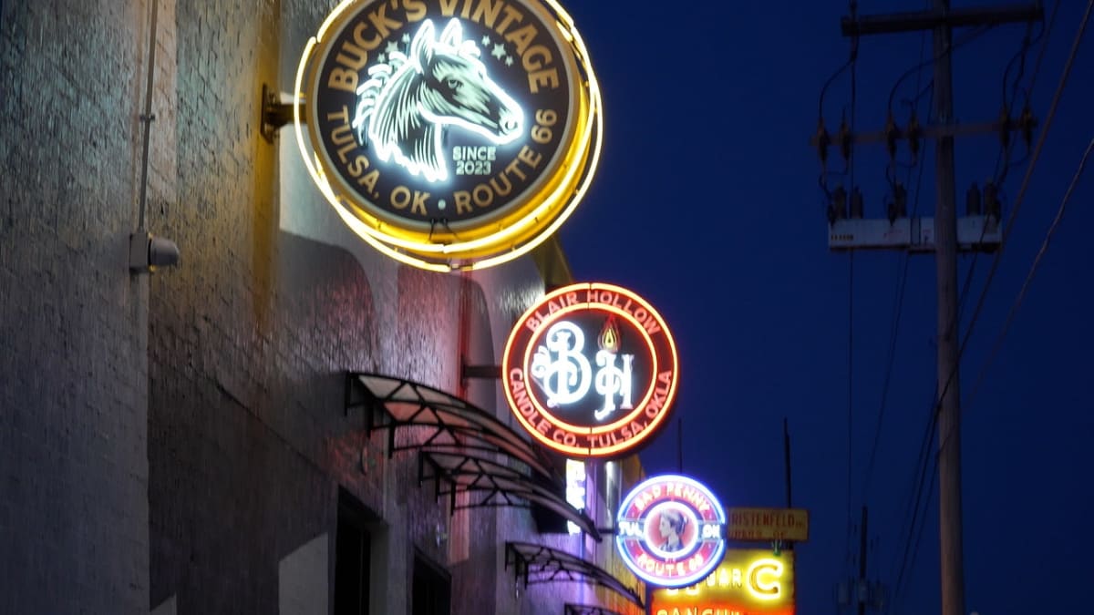 Bright neon signs illuminating historic Route 66 businesses along Tulsa's stretch at night