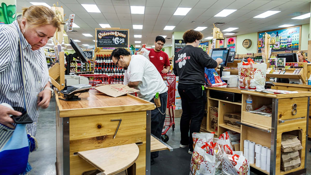 Smiling Trader Joe's employee helping customer at grocery store checkout lane