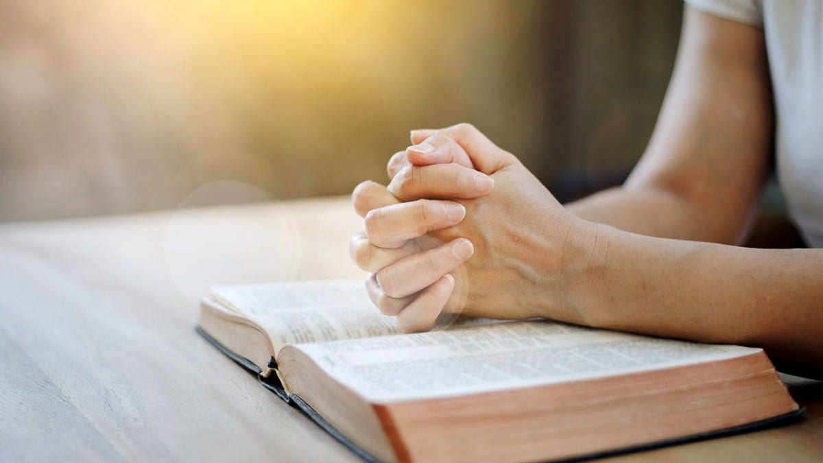 Two people sitting together in supportive prayer during medical appointment