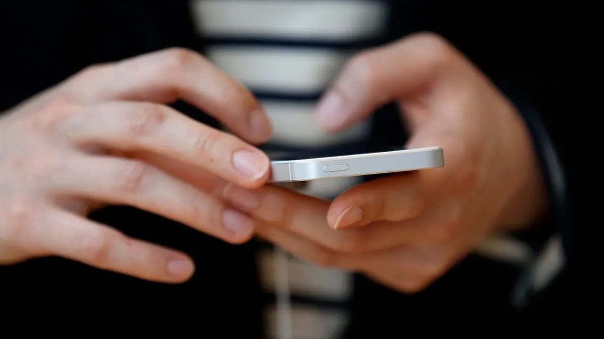 ** Elderly woman holding iPhone while adult son helps adjust privacy and security settings