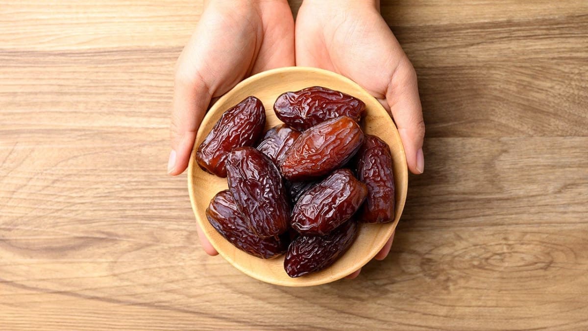Fresh medjool dates displayed in wooden bowl on rustic kitchen counter