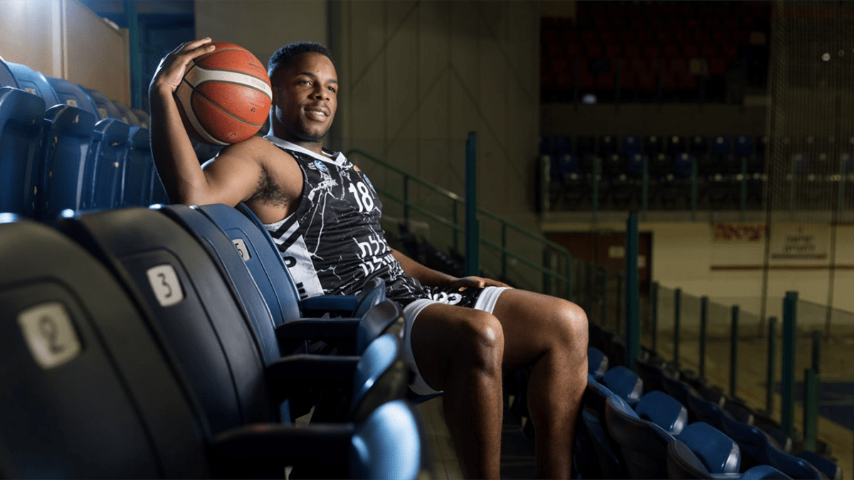 Jared Armstrong standing on newly built basketball court in Israel surrounded by young players