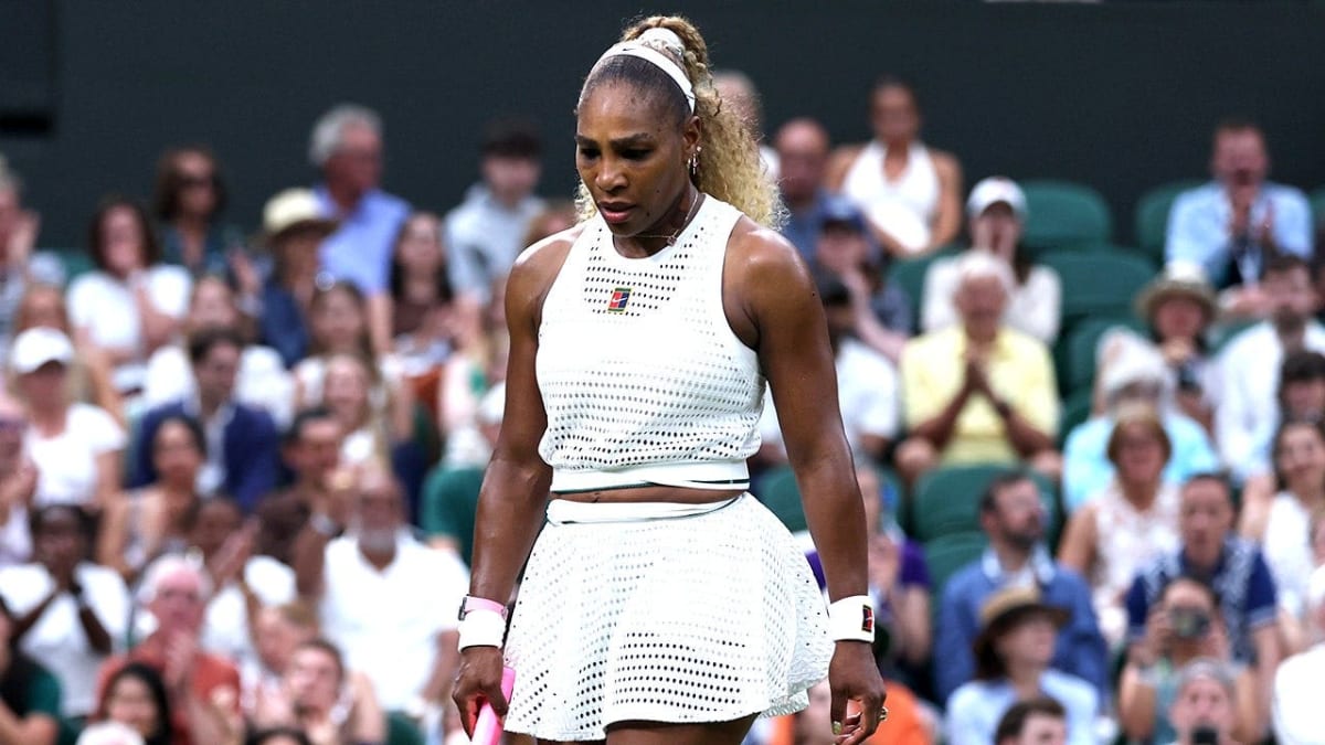 ** Serena Williams competing on grass court at Wimbledon wearing white tennis outfit