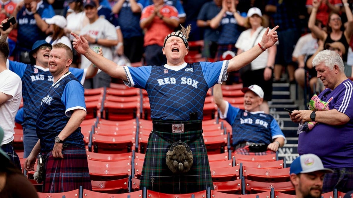 Scottish fans in traditional kilts playing bagpipes while marching to Fenway Park in Boston
