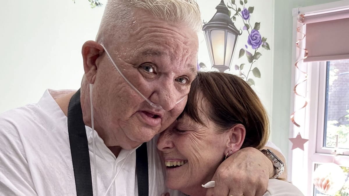 Dean Pennell and Kay Beaman smiling together at their hospital wedding ceremony surrounded by family