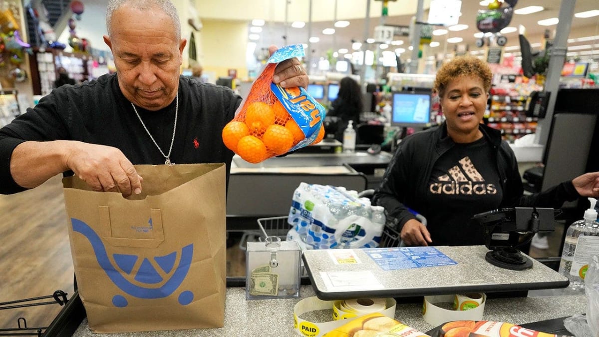Independent grocer arranging fresh produce in small neighborhood grocery store serving local community