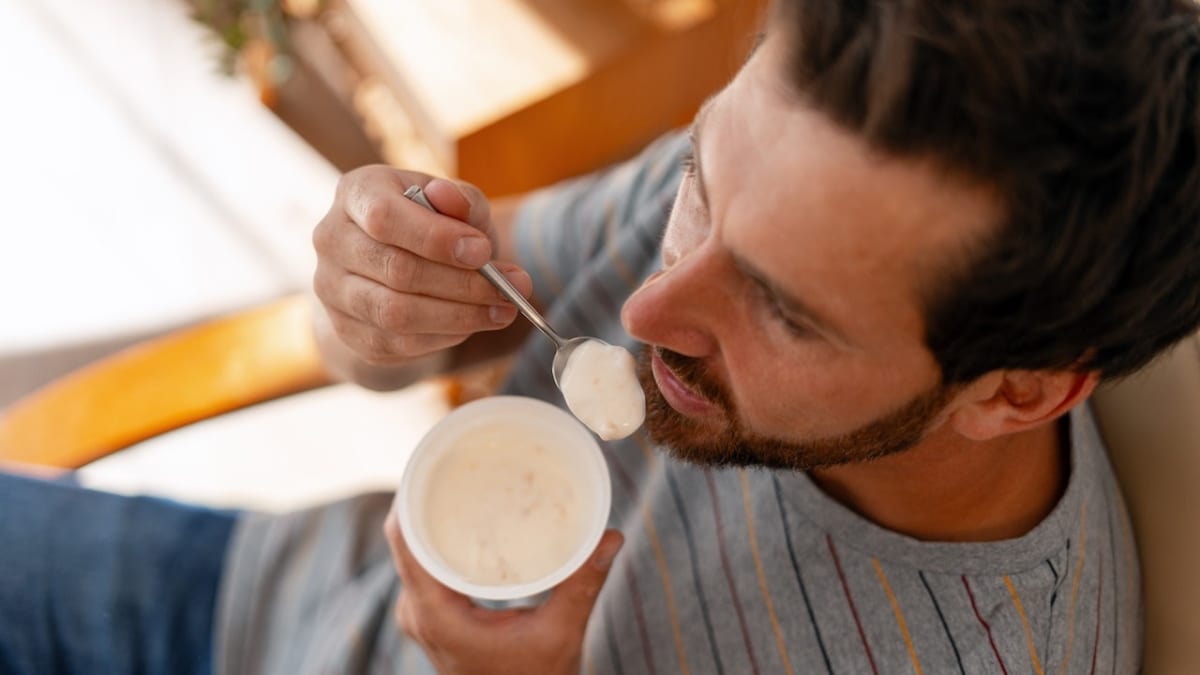 Middle-aged man eating plain yogurt from bowl, healthy lifestyle aging research concept