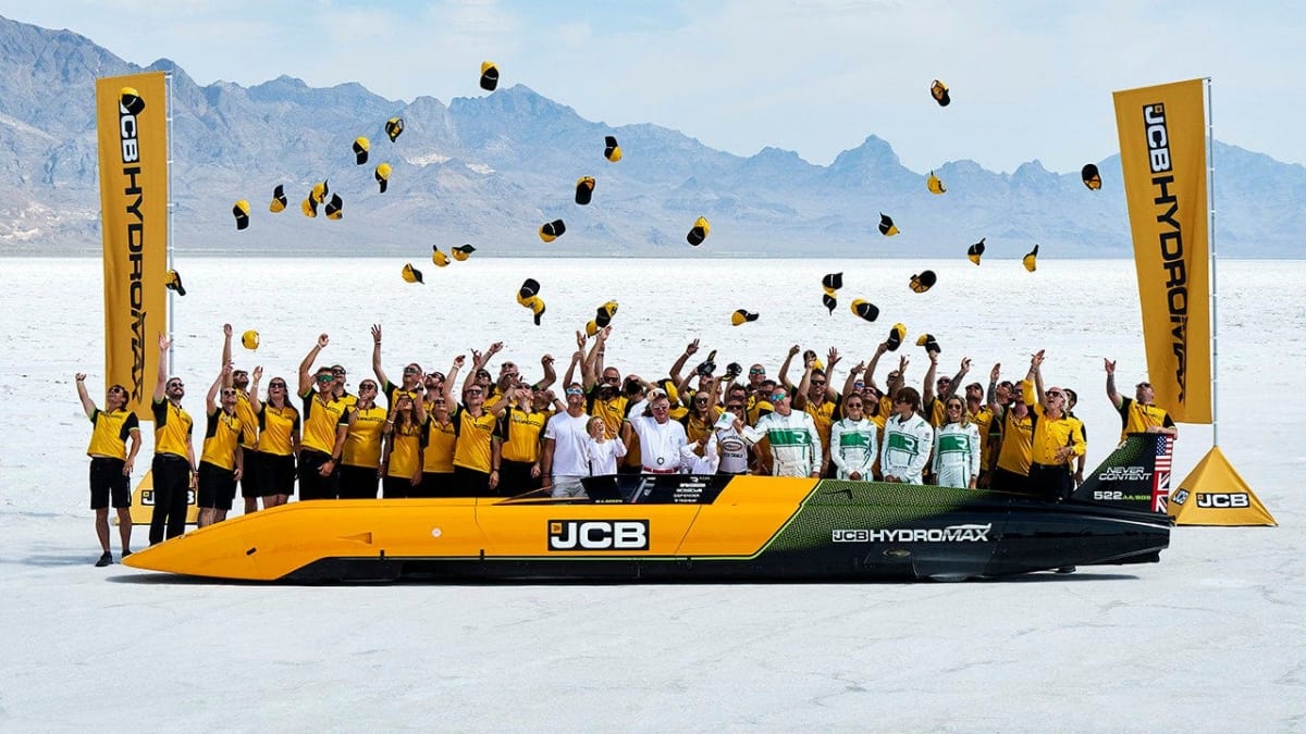 Silver hydrogen-powered JCB Hydromax racing car on white Bonneville Salt Flats under blue sky