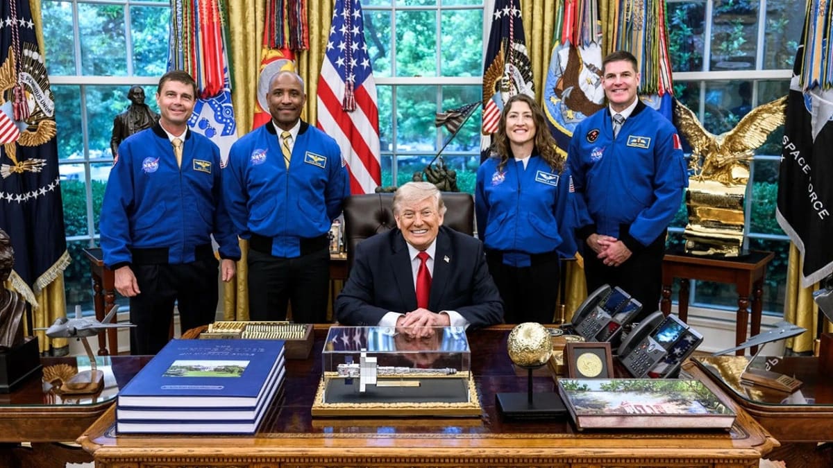 Four Artemis II astronauts in flight suits standing together at NASA facility smiling