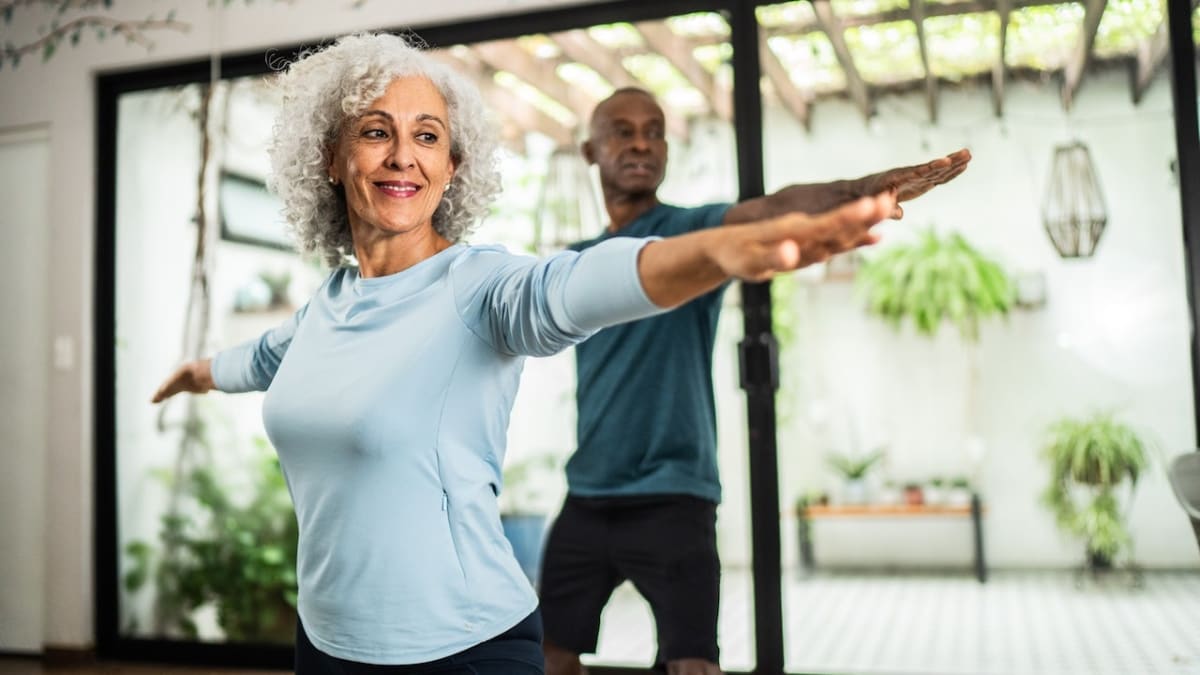 Older adult doing resistance training exercises with weights in bright fitness studio