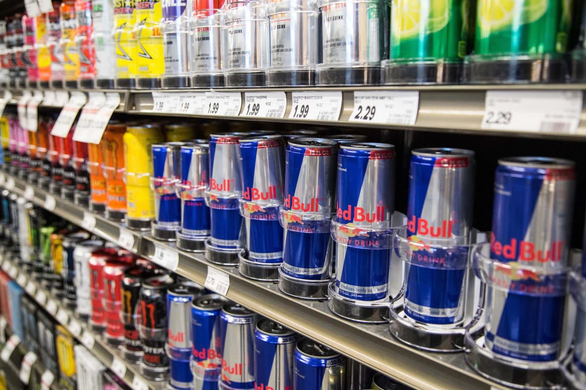 Colorful energy drink cans on store shelf with warning label visible on packaging