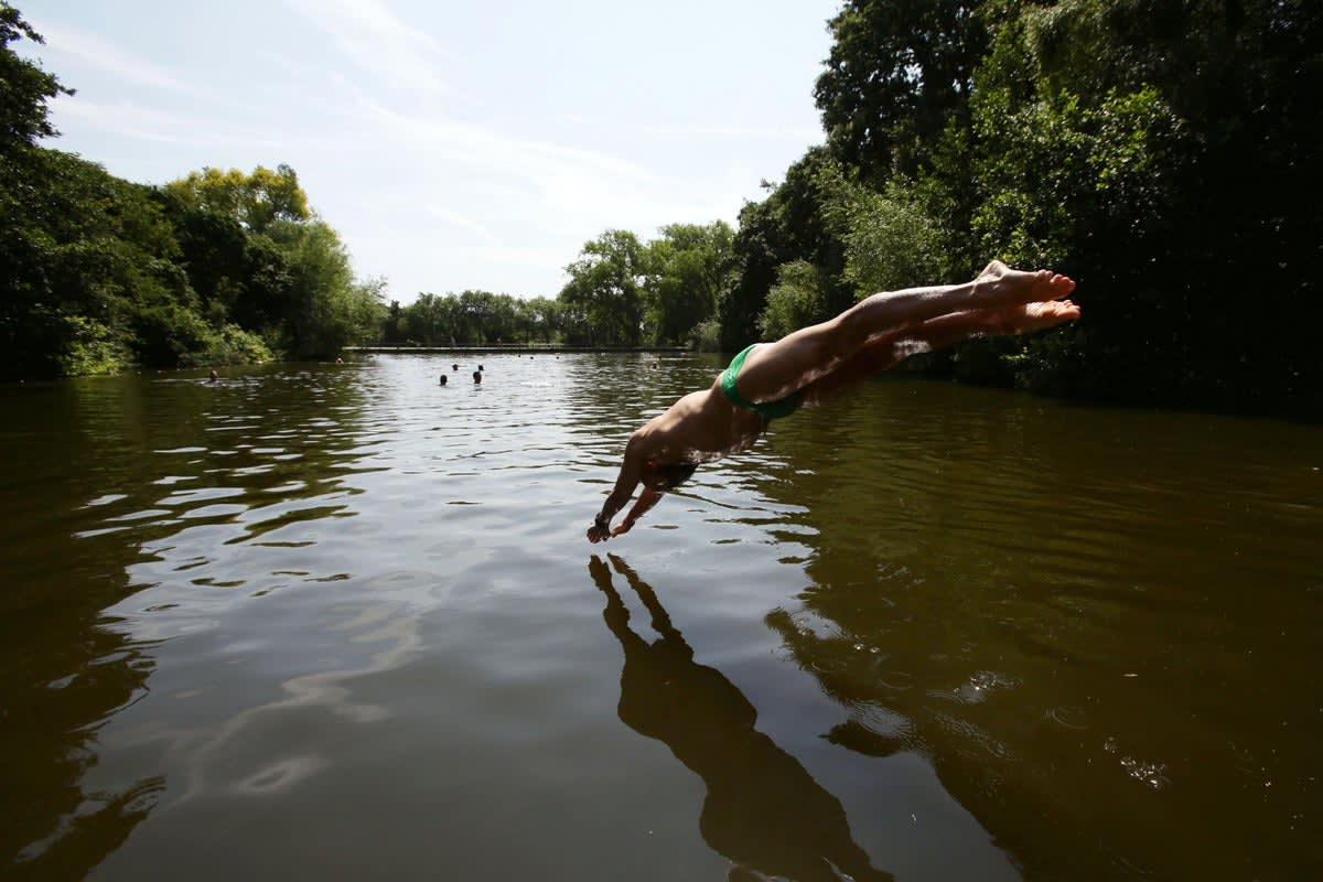 Historic Hampstead Heath bathing pond surrounded by trees with calm water reflecting sky