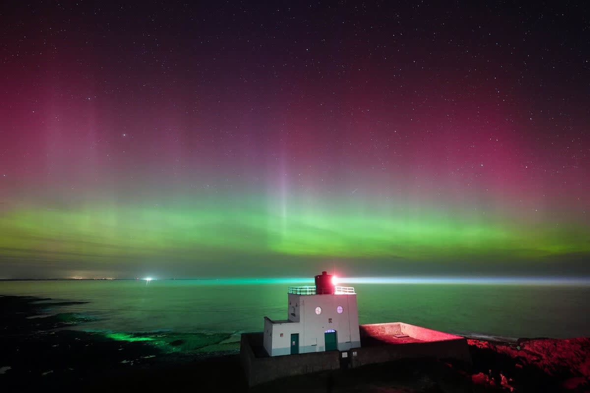 Brilliant green Northern Lights illuminate the night sky over Bamburgh Castle in Northumberland, England