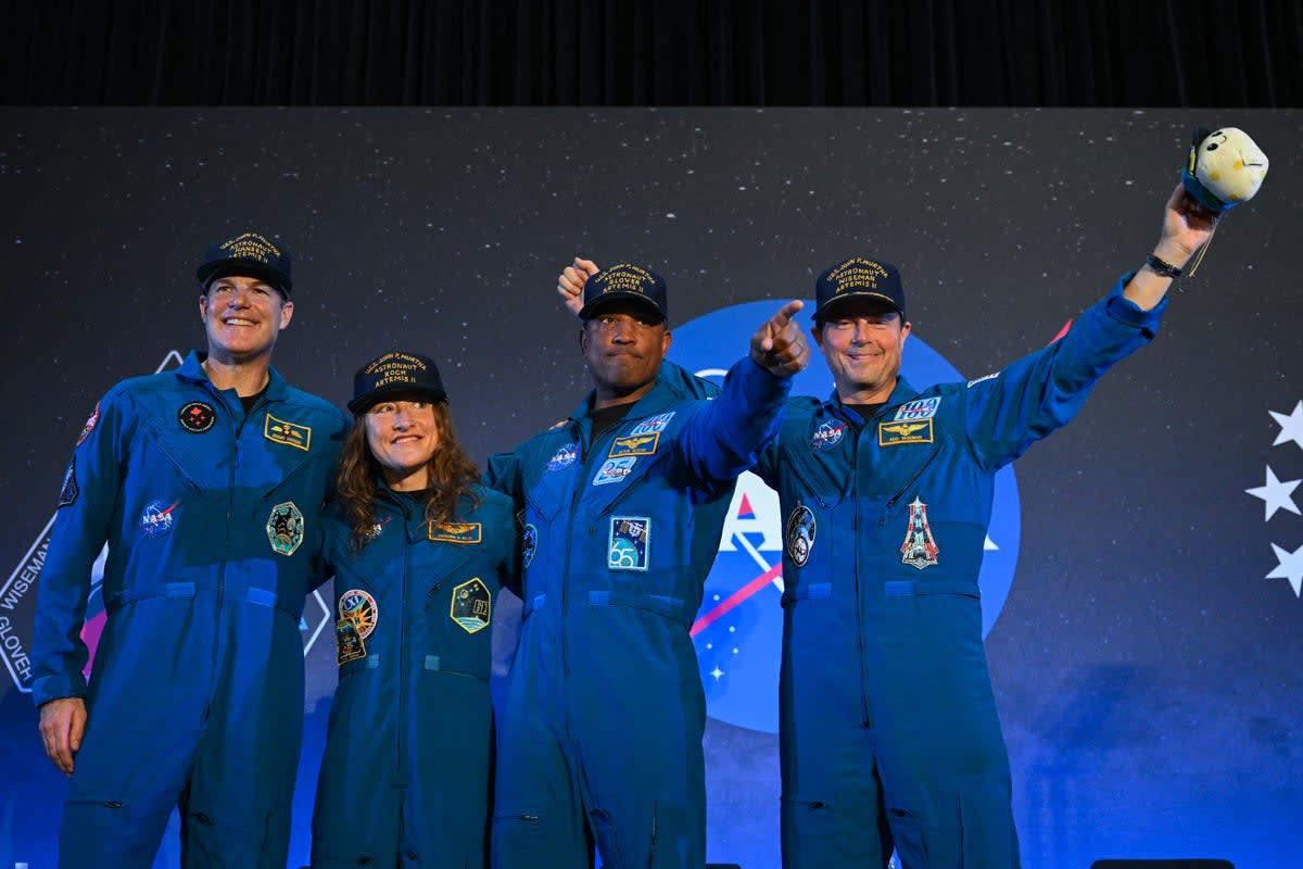 Four smiling Artemis II astronauts in blue flight suits celebrating their successful Moon mission return