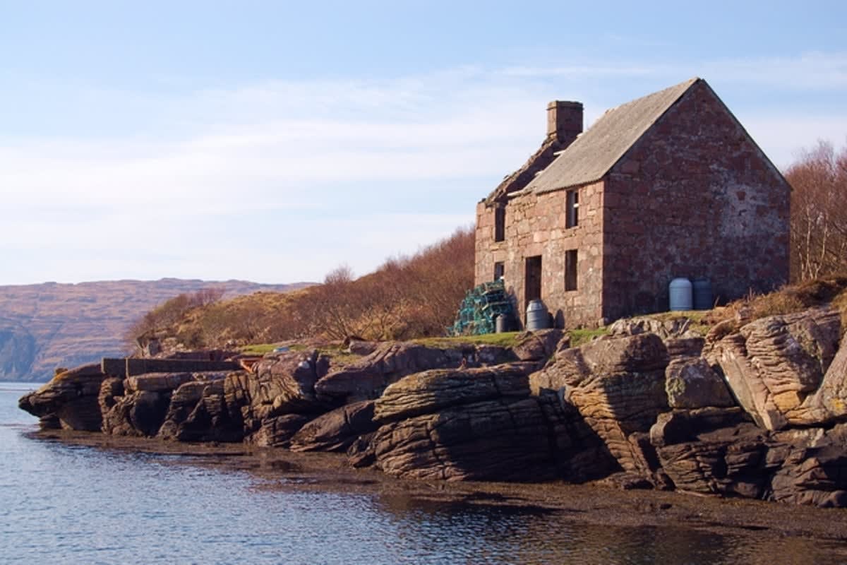 Remote Scottish cottage overlooking bay with dramatic Black Cuillin mountains in background