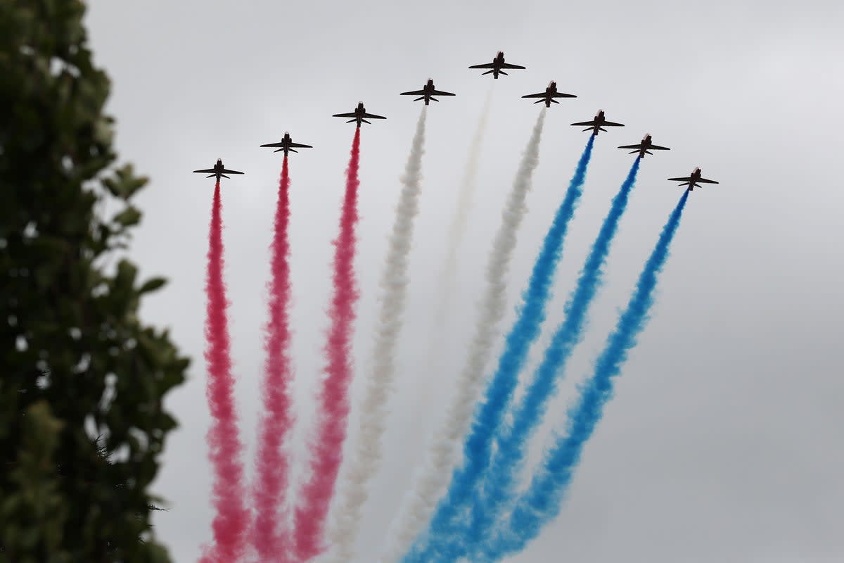Red Arrows aerobatic team jets flying in precise formation trailing red smoke across blue sky