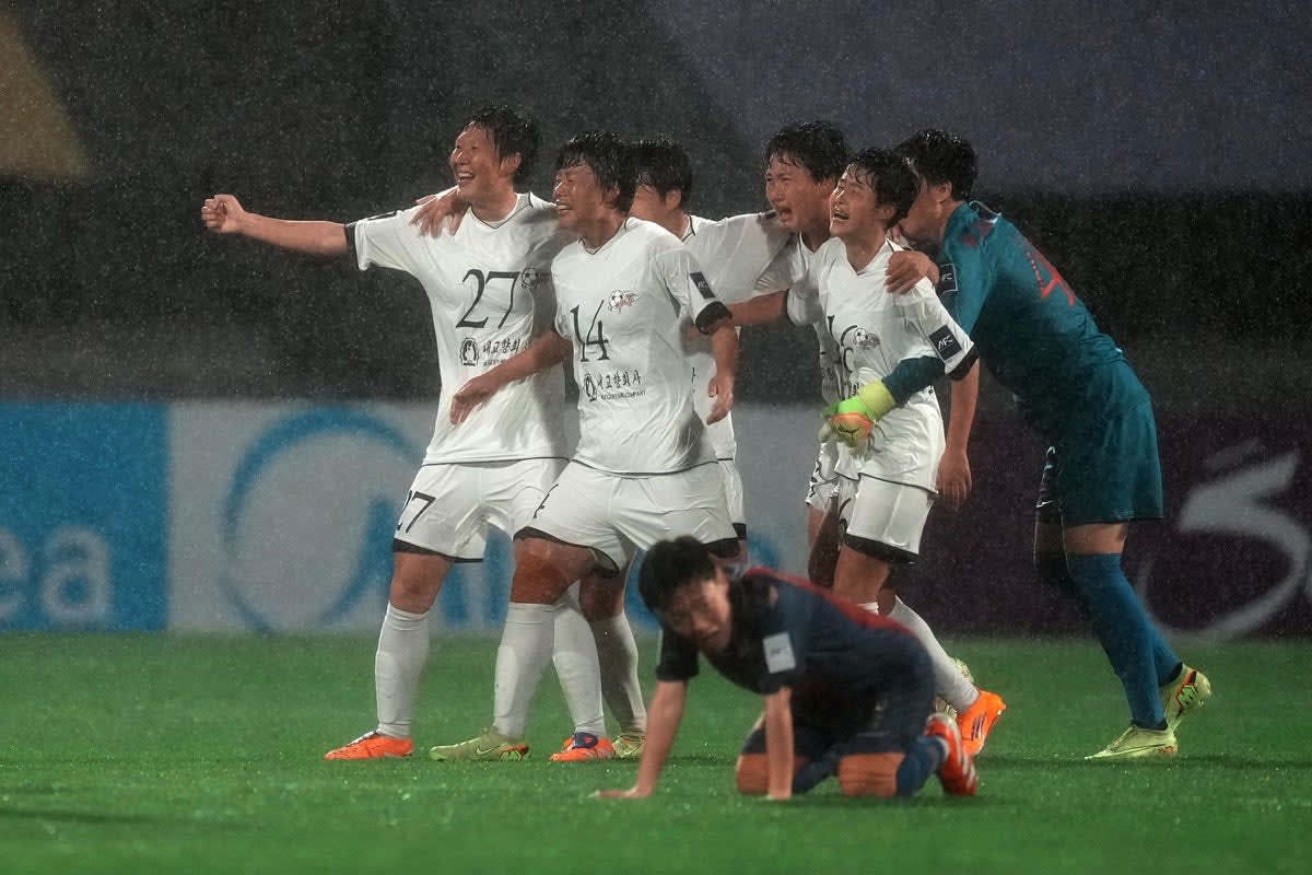 ** North Korean women's football players celebrating victory in rain-soaked stadium in South Korea