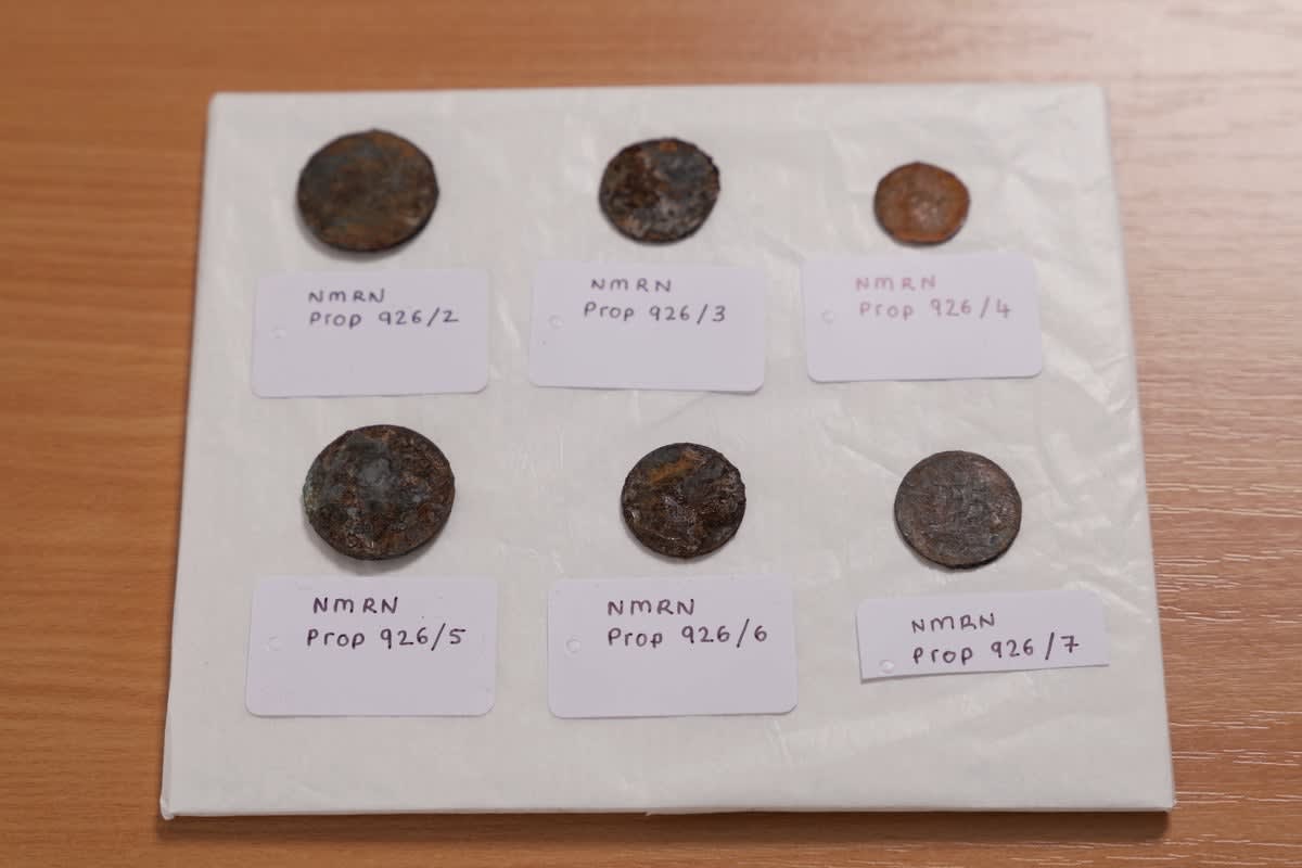 Six corroded 19th-century coins laid out after discovery beneath HMS Victory's foremast