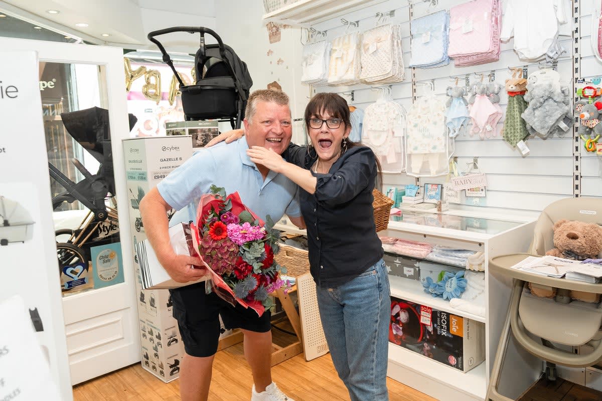 Former delivery driver Gary MacDonald smiling with former colleague holding flowers at Lakeside Shopping Centre