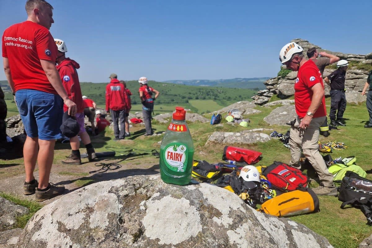 Rescue workers surrounding large granite rocks on Hound Tor in Dartmoor, Devon during emergency operation