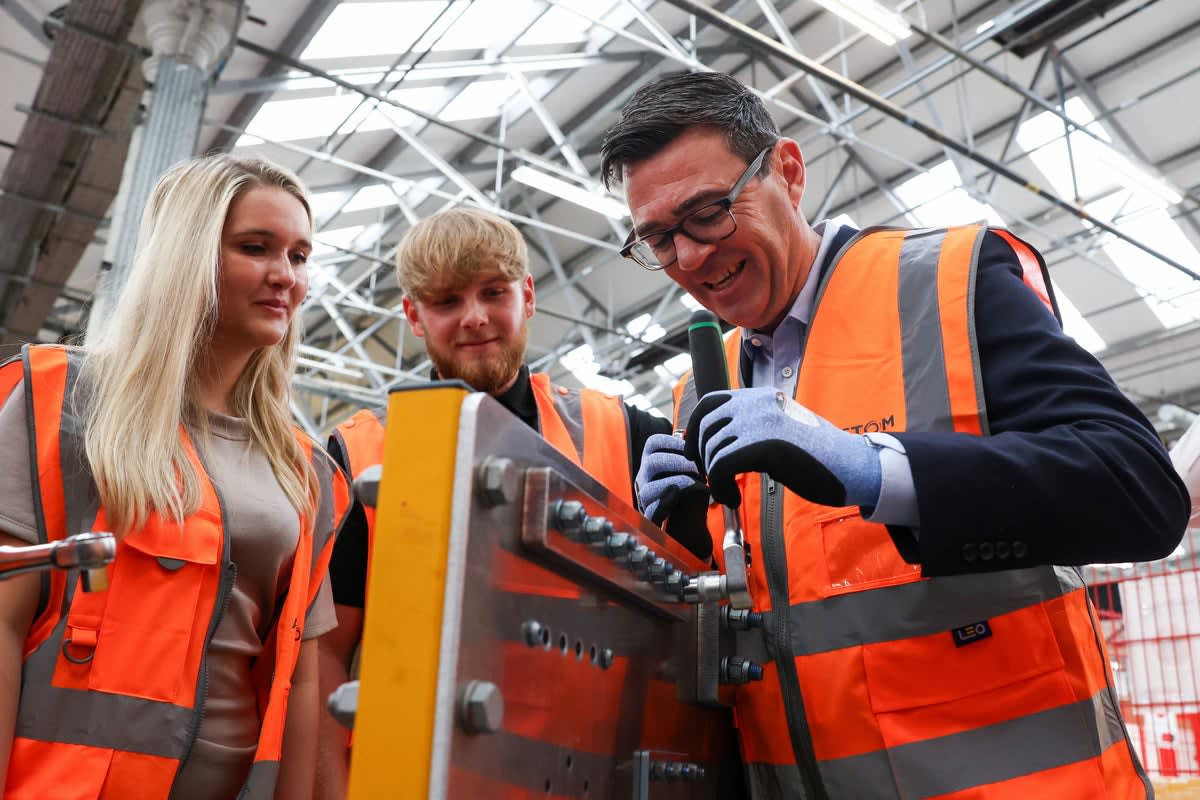 Young apprentice learning technical skills in workshop setting with supportive instructor nearby