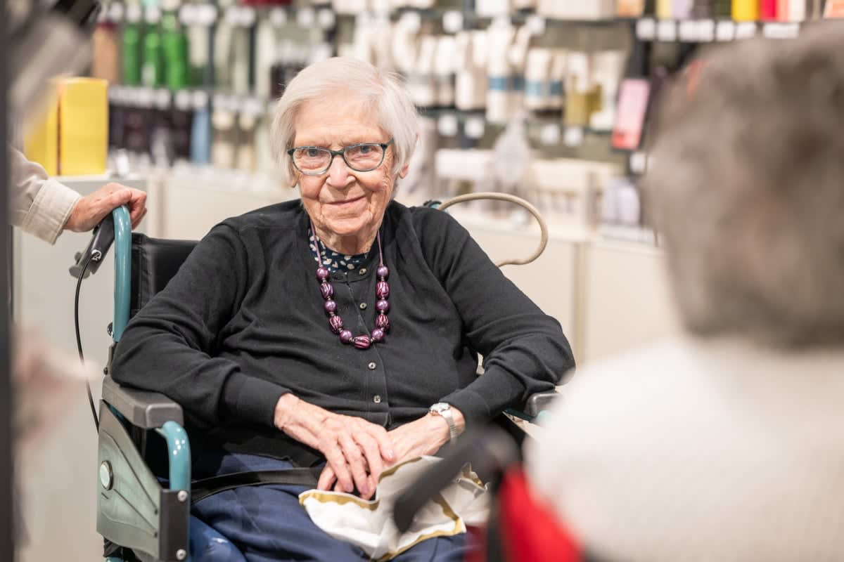 Three elderly women smiling outside Marks and Spencer store in Aberdeen, Scotland