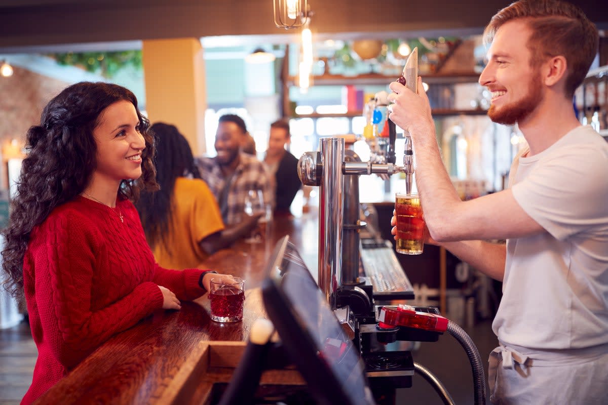 Bartender scanning customer's phone showing digital ID at pub bar counter