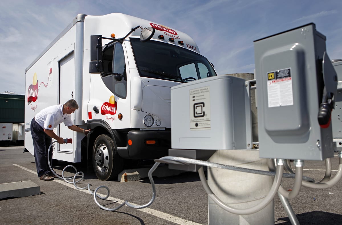 Electric semi-truck charging at station with California landscape in background