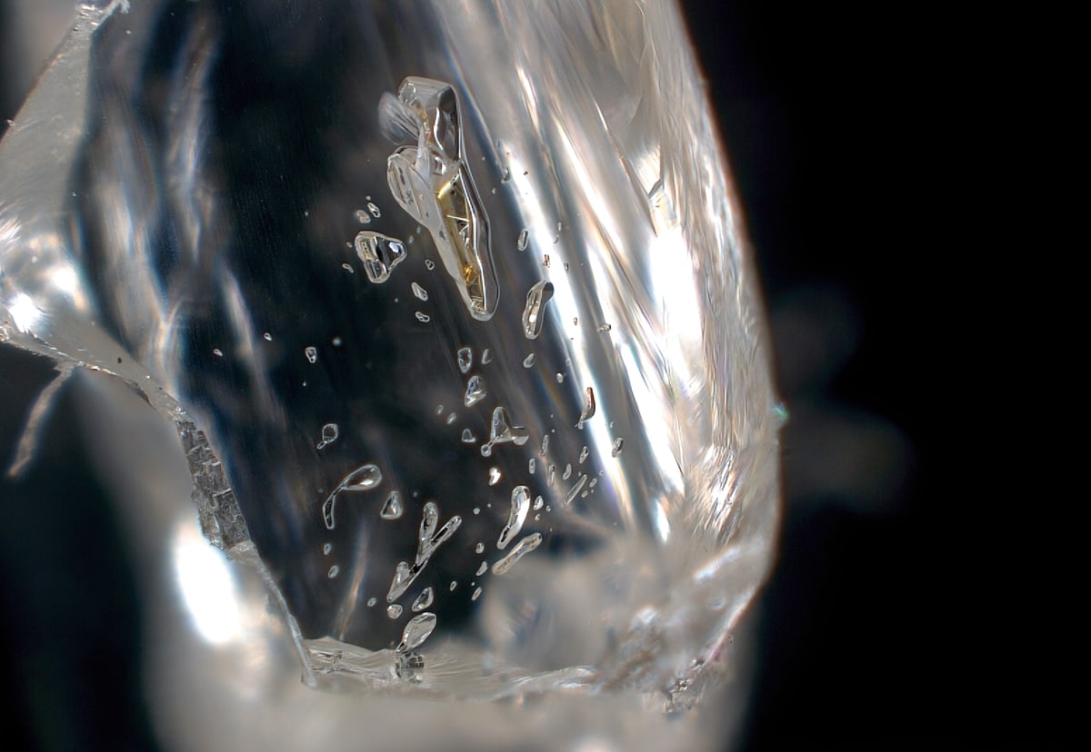 Close-up microscope view of tiny mineral inclusion trapped inside transparent diamond crystal
