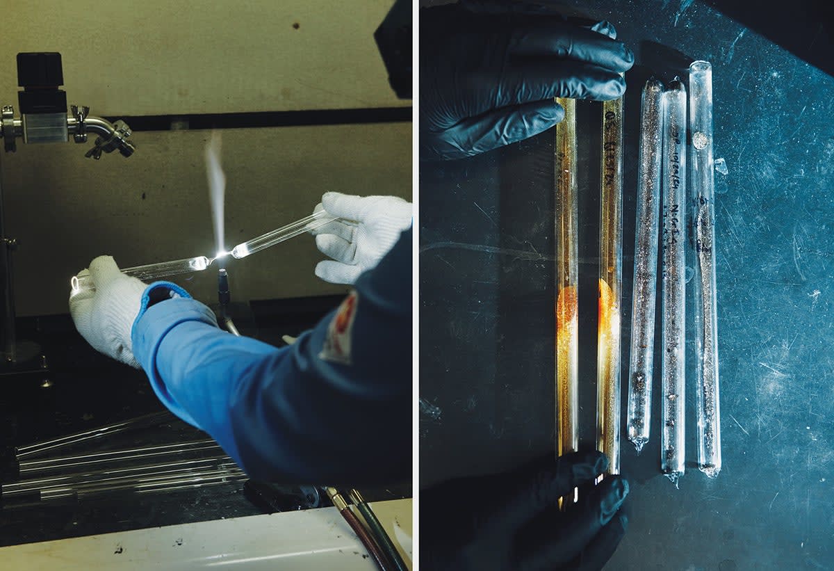 Graduate student examining tiny golden crystal flakes on purple silicon wafer under laboratory lighting