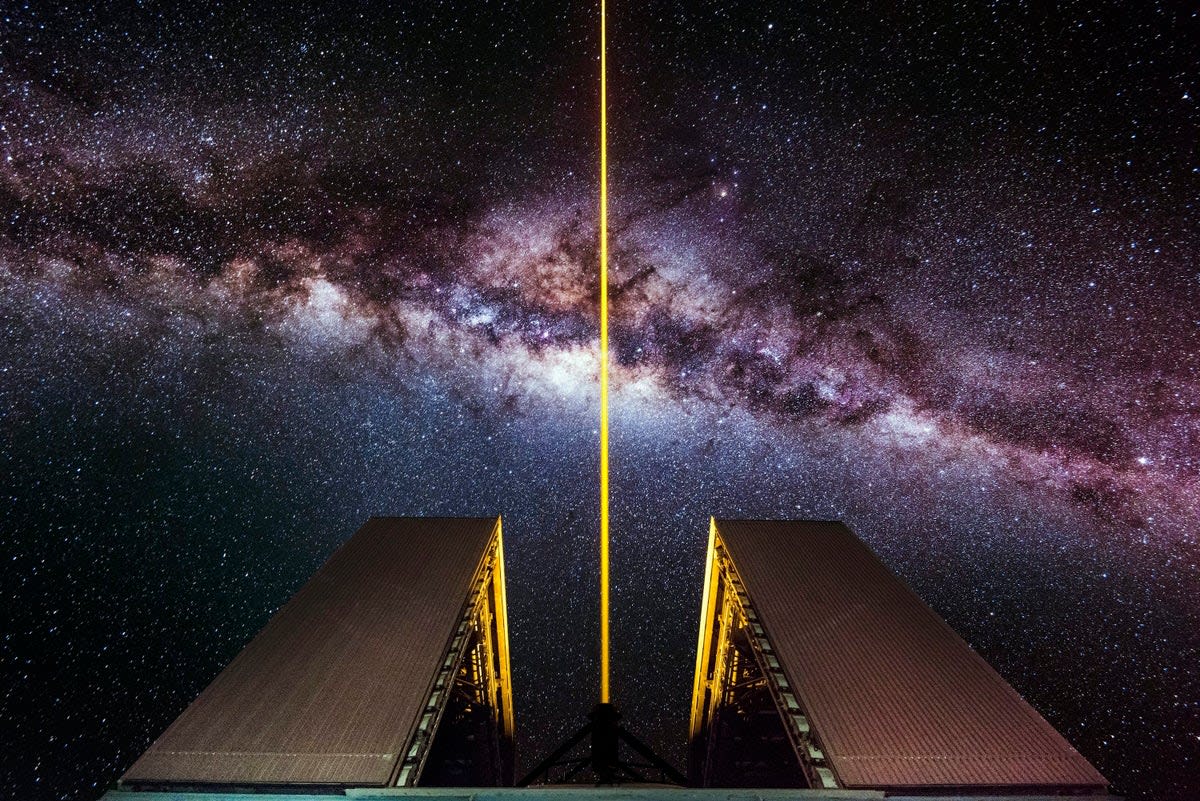 Laser beam shooting into night sky from large optical telescope at Chilean observatory